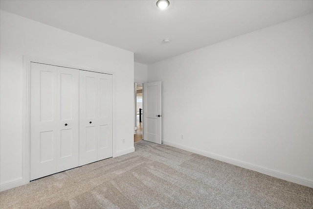 unfurnished bedroom with light colored carpet and a closet