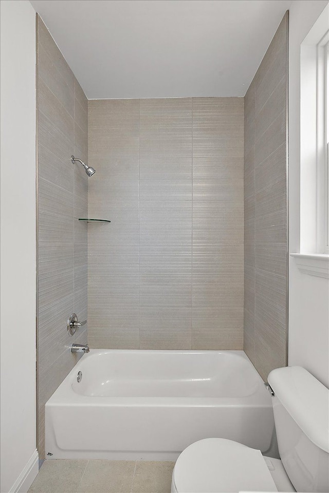 bathroom with tile patterned flooring, tiled shower / bath combo, and toilet