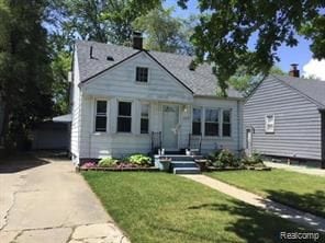 view of front of home featuring an outbuilding, a front lawn, and a garage