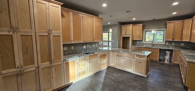 kitchen with light stone counters, sink, backsplash, and hanging light fixtures