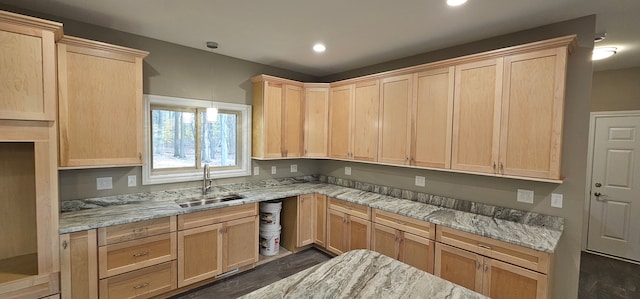 kitchen with light brown cabinetry, light stone countertops, and sink