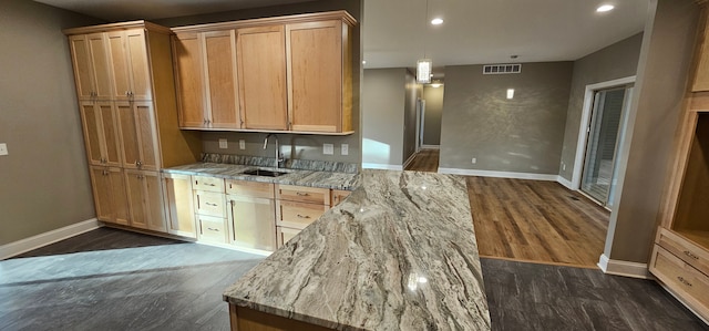 kitchen featuring dark wood-type flooring, light stone countertops, sink, and light brown cabinets