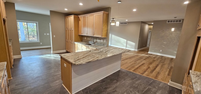 kitchen with dark wood-type flooring, light brown cabinetry, sink, ceiling fan, and light stone countertops