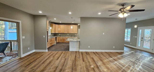 kitchen featuring decorative light fixtures, sink, dark hardwood / wood-style flooring, light stone countertops, and light brown cabinets