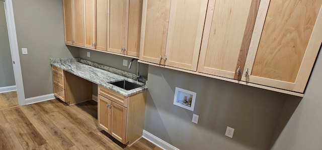 clothes washing area with light hardwood / wood-style floors, cabinets, hookup for a washing machine, and sink