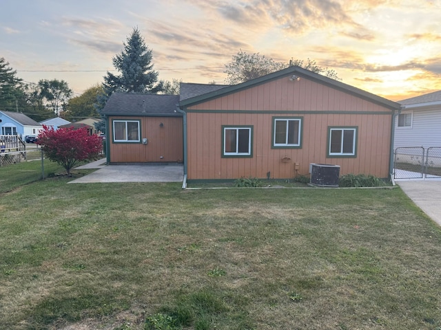 back house at dusk with a patio area and a lawn