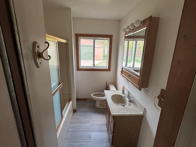 full bathroom featuring hardwood / wood-style floors, vanity, toilet, and enclosed tub / shower combo