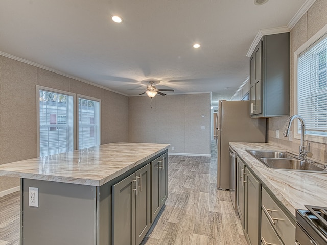 kitchen featuring gray cabinetry, crown molding, sink, light hardwood / wood-style floors, and a kitchen island