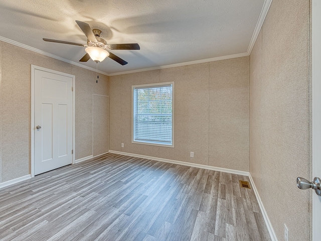 empty room with a textured ceiling, light wood-type flooring, ceiling fan, and crown molding