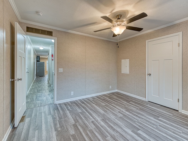 spare room with a textured ceiling, ceiling fan, crown molding, light hardwood / wood-style flooring, and electric panel