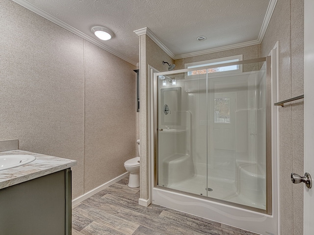 bathroom with crown molding, toilet, vanity, a shower with shower door, and hardwood / wood-style flooring