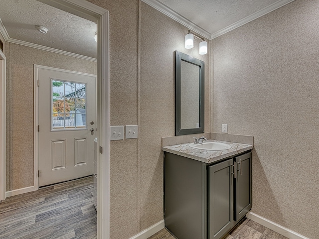 bathroom featuring wood-type flooring, vanity, a textured ceiling, and ornamental molding