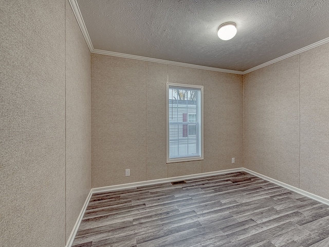 empty room with hardwood / wood-style floors, a textured ceiling, and crown molding