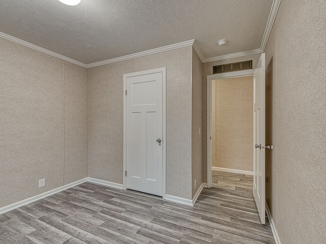 interior space featuring crown molding, light hardwood / wood-style flooring, and a textured ceiling