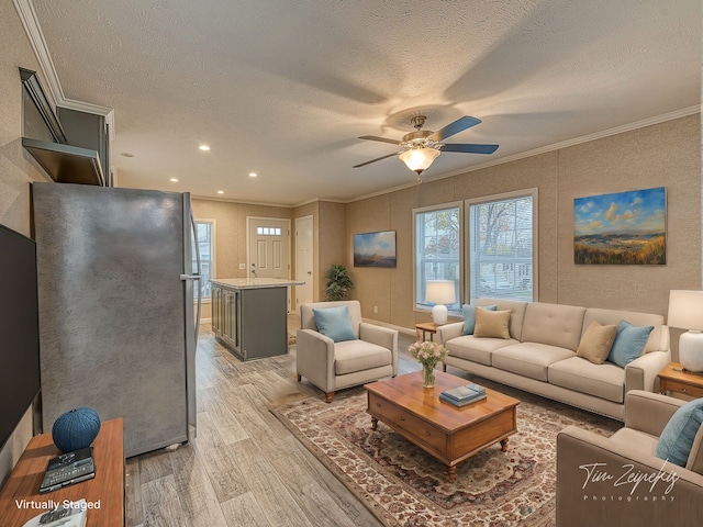 living room with ceiling fan, light wood-type flooring, a textured ceiling, and ornamental molding