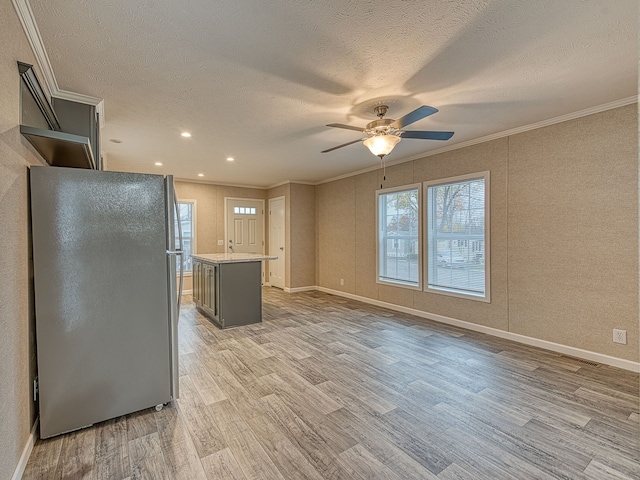 kitchen with stainless steel refrigerator, light hardwood / wood-style flooring, a kitchen island, and a textured ceiling