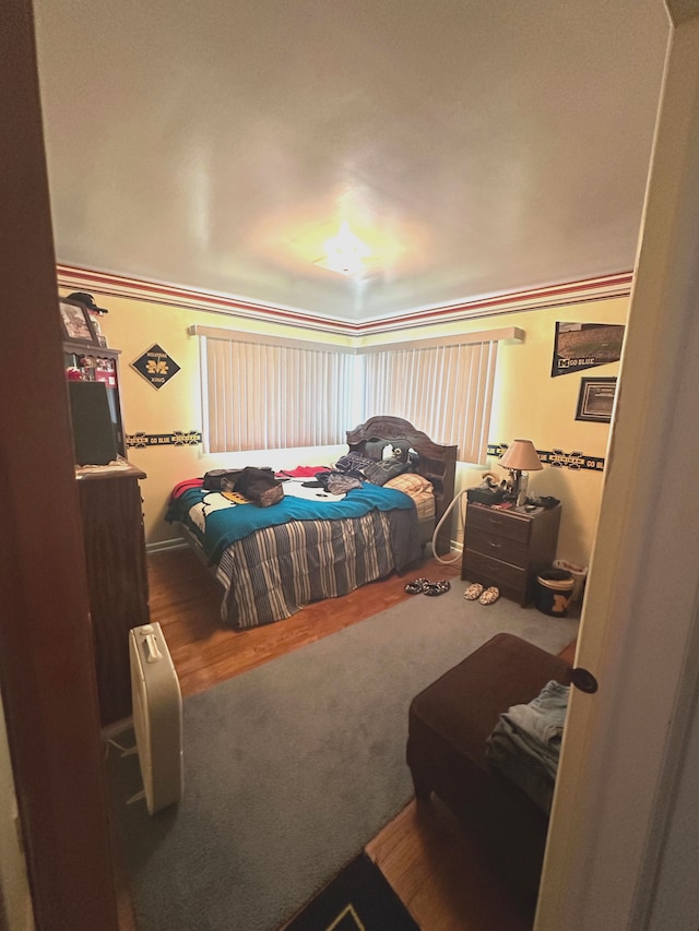 bedroom with wood-type flooring and crown molding