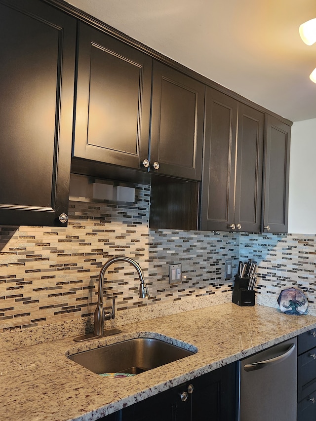 kitchen featuring dishwasher, tasteful backsplash, light stone countertops, and sink