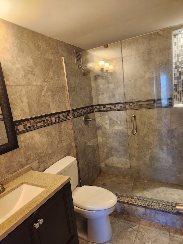 bathroom with toilet, an enclosed shower, tile walls, and vanity