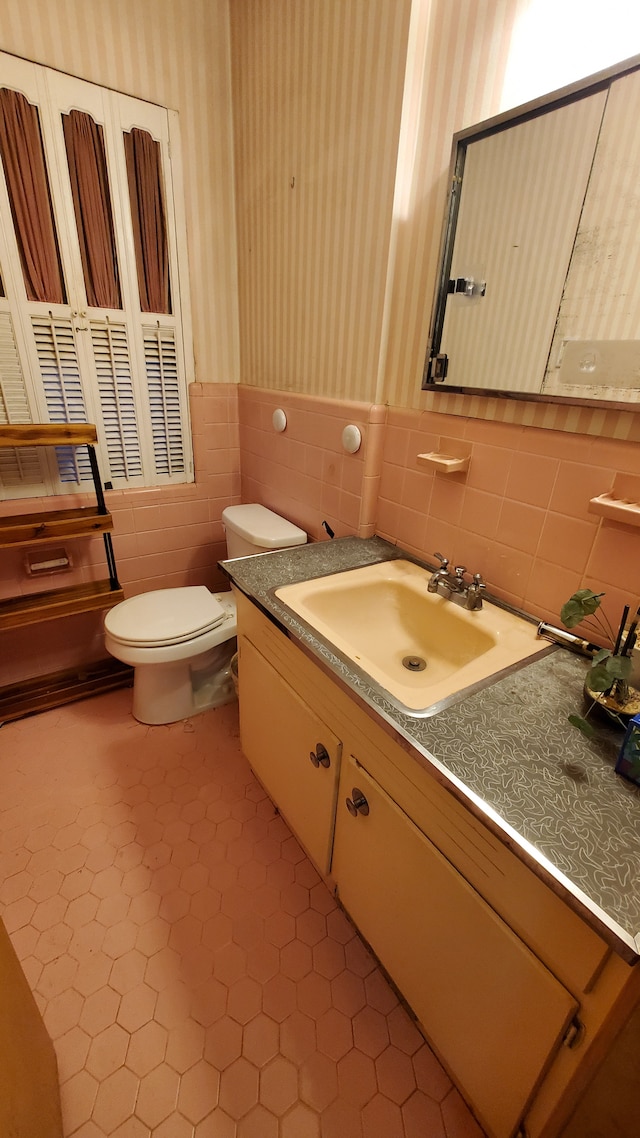 bathroom with tile patterned flooring, vanity, toilet, and tile walls