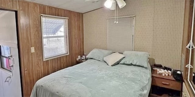 bedroom featuring ceiling fan and wood walls