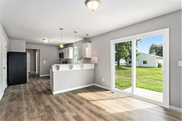 kitchen with kitchen peninsula, plenty of natural light, white cabinets, and stainless steel appliances