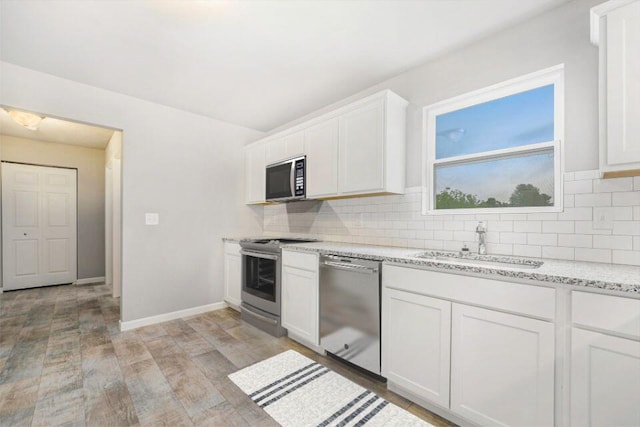 kitchen with decorative backsplash, white cabinetry, sink, and appliances with stainless steel finishes