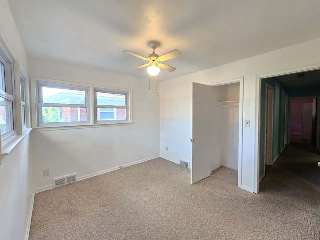 unfurnished bedroom featuring ceiling fan, a closet, and light colored carpet