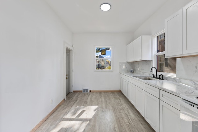 kitchen featuring tasteful backsplash, sink, white cabinets, and light wood-type flooring