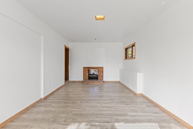 unfurnished living room with a wood stove and light wood-type flooring