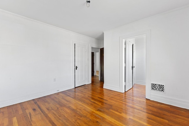 empty room with wood-type flooring and crown molding