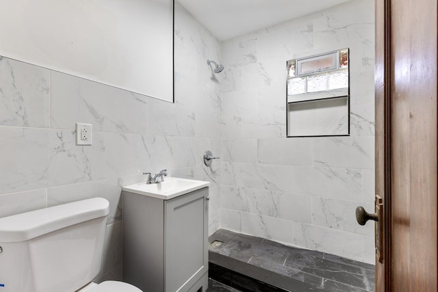 bathroom with tiled shower, vanity, tile walls, and toilet