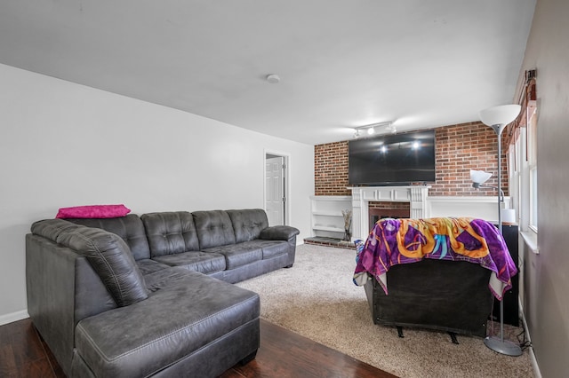 living room featuring rail lighting, dark hardwood / wood-style floors, and a brick fireplace