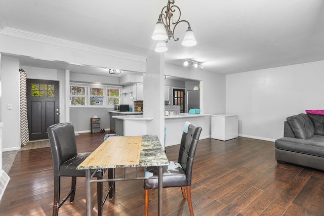 dining space featuring a notable chandelier, dark hardwood / wood-style floors, and ornamental molding