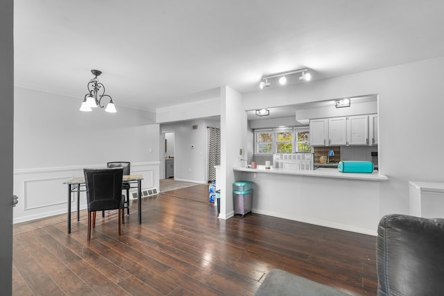 kitchen with hanging light fixtures, dark hardwood / wood-style floors, a notable chandelier, kitchen peninsula, and white cabinets