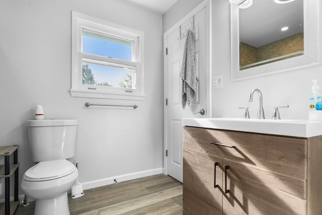 bathroom with toilet, vanity, and hardwood / wood-style flooring