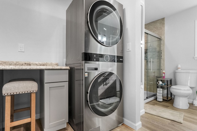 washroom featuring light wood-type flooring and stacked washer and clothes dryer