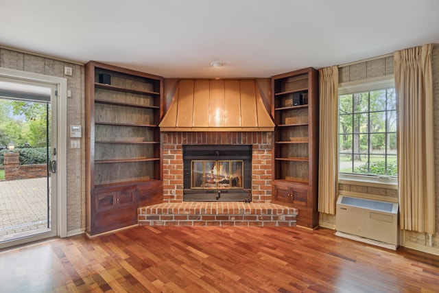 unfurnished living room featuring hardwood / wood-style floors, plenty of natural light, and a brick fireplace