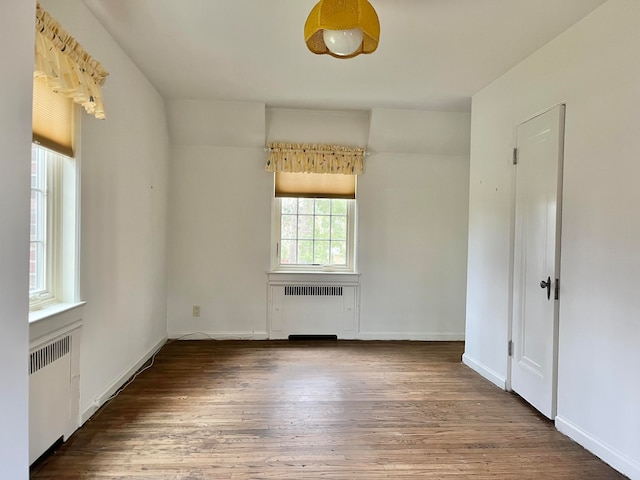 empty room with radiator and dark hardwood / wood-style flooring