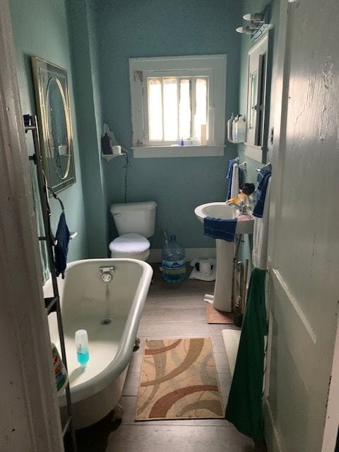 bathroom with hardwood / wood-style flooring, toilet, and a bathtub