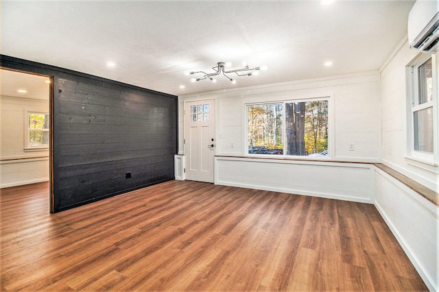 unfurnished room with an inviting chandelier, hardwood / wood-style flooring, a wall unit AC, and wood walls