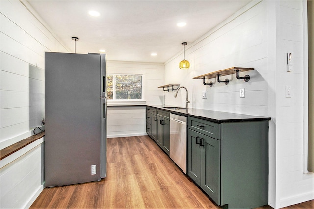 kitchen with ornamental molding, stainless steel appliances, sink, pendant lighting, and light hardwood / wood-style floors