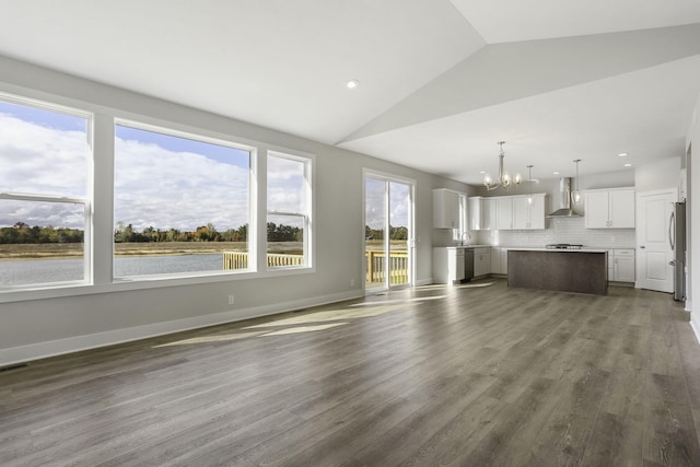 unfurnished living room with an inviting chandelier, a water view, sink, vaulted ceiling, and dark hardwood / wood-style floors