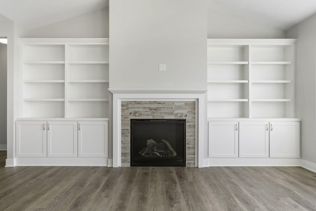 unfurnished living room featuring a stone fireplace, dark hardwood / wood-style floors, and lofted ceiling