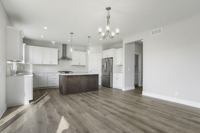 kitchen with stainless steel refrigerator with ice dispenser, dark hardwood / wood-style flooring, wall chimney exhaust hood, white cabinets, and a center island