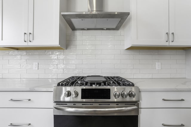 kitchen featuring white cabinetry, light stone counters, stainless steel gas stove, and wall chimney exhaust hood