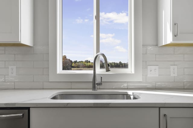 details with light stone counters, sink, and white cabinets