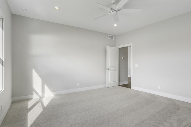 empty room with ceiling fan and light carpet