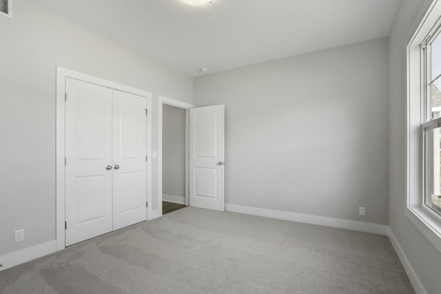 unfurnished bedroom featuring light carpet and a closet