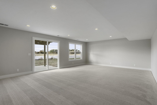 carpeted spare room featuring a water view